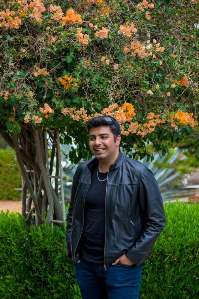 a man standing in front of a tree with orange flowers